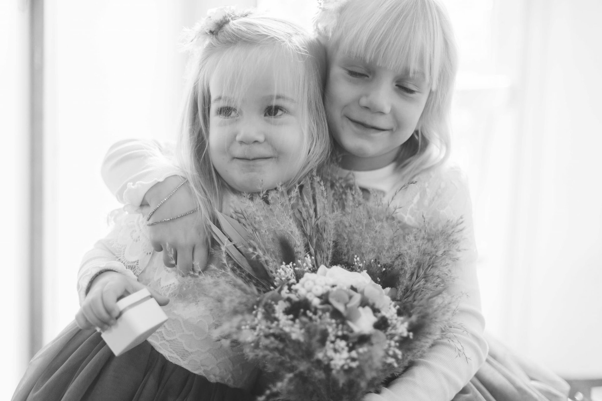 Deux petites demoiselles d'honneur joue contre joue tenant un bouquet de fleurs — moment de tendresse, mariage Saint-Génis-des-Fontaines