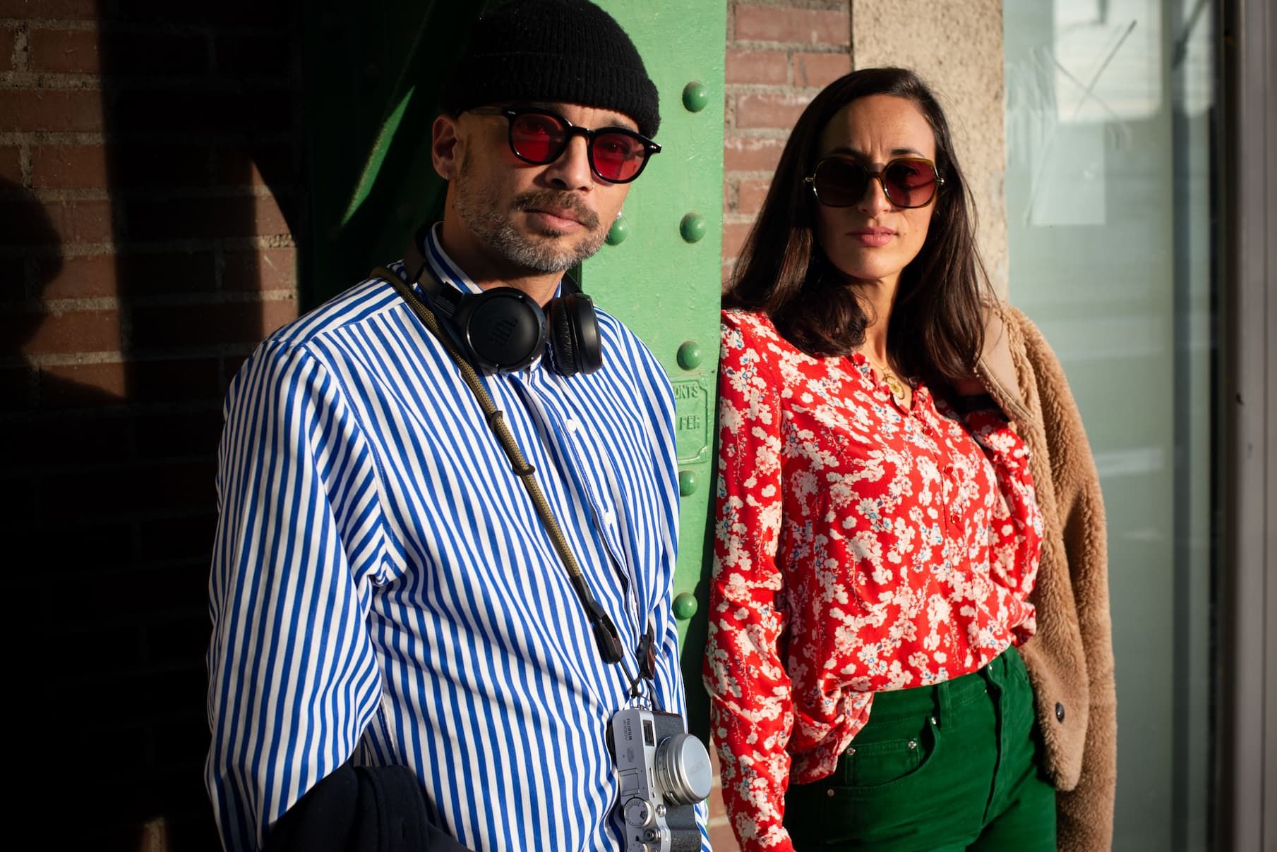 Couple en lunettes de soleil appuyé contre un mur, style urbain décontracté — séance engagement Perpignan