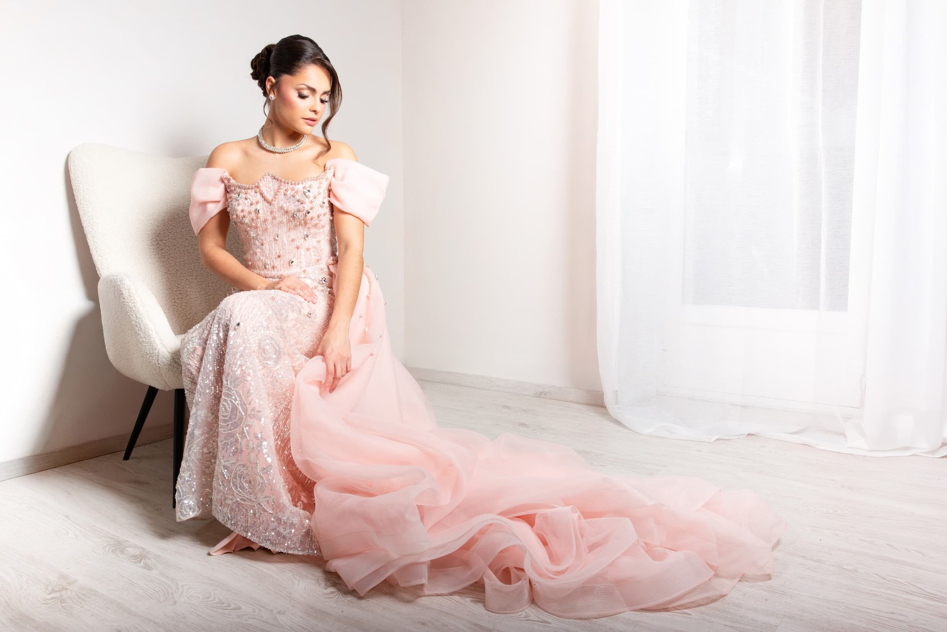 Modèle en robe de bal rose brodée à longue traîne, assise sur un fauteuil blanc — shooting inspiration mariage